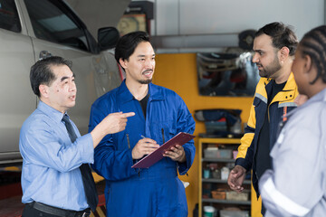 Manager, mechanics and customer discussing together at auto car repair service. Car service and...
