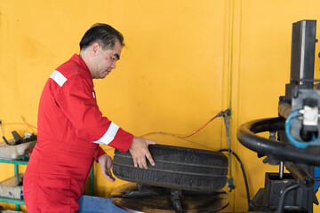 Male mechanic working at garage. Senior Asian male mechanics checking tire wheel at auto car repair...