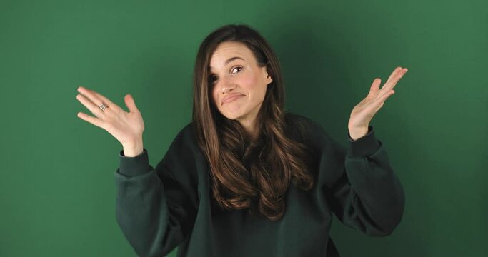 Young woman making good-bad sign isolated on green background. Girl make choice, or makes a decision thumb up or thumb down, like or dislike, yes or no. Woman change emotions, raised hands.