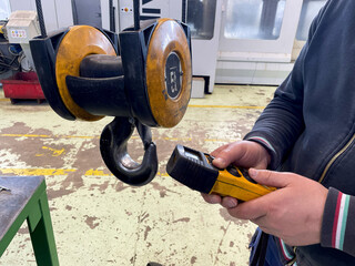working hands, yellow remote control for overhead crane, with 5 ton hook holding steel mold