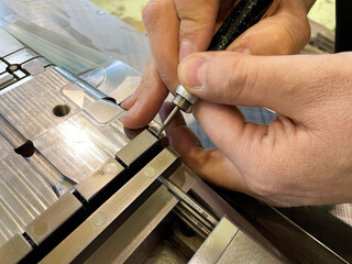 working hands, finishing with a precision tool on a steel mould