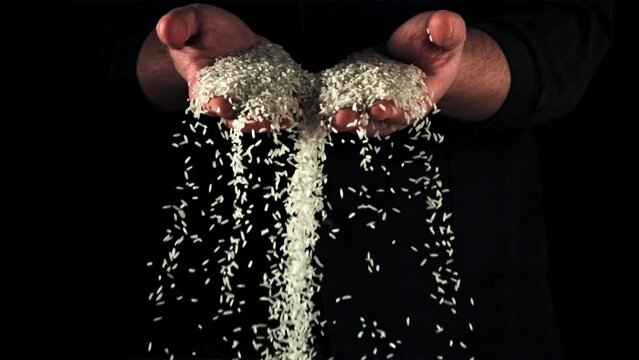 Super slow motion from men's palms pours raw rice . High quality FullHD footage
