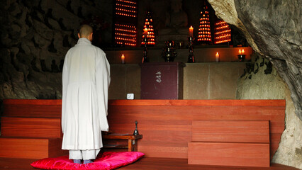 A monk in ritual dress prays in a Buddhist temple. Beautiful interior of a Buddhist temple