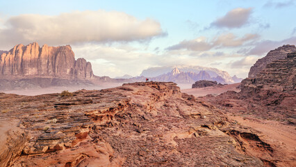 Red orange sandstone rocks formations in Wadi Rum - two small persons at distance (also known as...