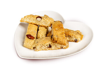 A heart shaped plate of biscotti cookies with almonds and chocolate chips isolated on white