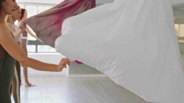 Group of women with instructor preparing hammocks for an aerial yoga session, symbolizing health and teamwork.