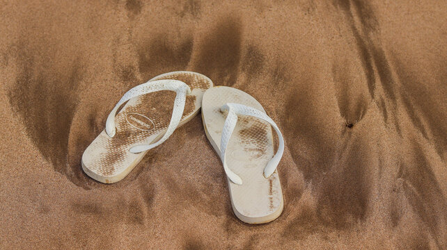 Chinelo branco havaianas coberto com água do mar na praia de são miguel dos milagres, alagoas. Foto feita em Alagoas em 01 Abril 2024