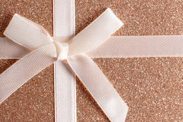 Closeup of ribbon bow on a shiny surface background, copy space bar.