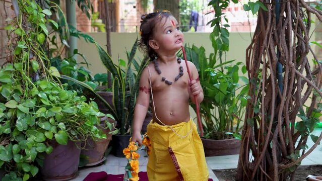 Cute Indian boy dresses as lord rama in action with bow at outdoor with from different angle at day