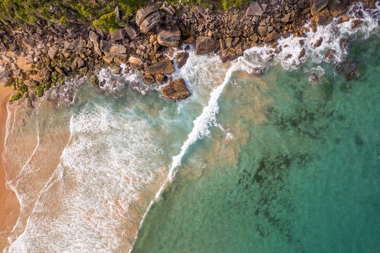 Aerial view of surf breaking over rocks and sand at Palm Beach, Sydney Northern Beaches, Australia
