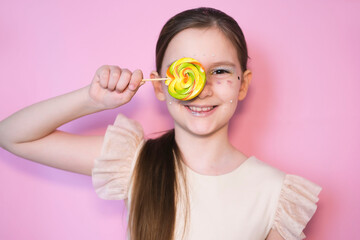 Portrait of happy smiling little girl with lollipop. Sugar for children. Little sweet tooth on pink...