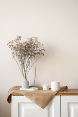 Dried flower vase on wood table with candles, creating a serene interior design, vertical home...