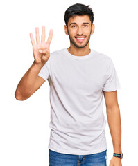 Naklejka premium Young handsome man wearing casual white tshirt showing and pointing up with fingers number four while smiling confident and happy.