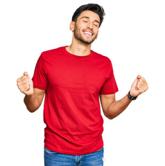 Young handsome man wearing casual red tshirt very happy and excited doing winner gesture with arms...