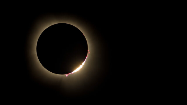 Awe-inspiring color photo of the 2024 solar eclipse showing diamond ring effect and solar prominence with red  plasma shooting from the sun's surface. Photo taken from Carbondale Illinois area.