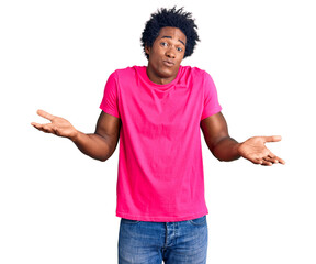 Handsome african american man with afro hair wearing casual pink tshirt clueless and confused...