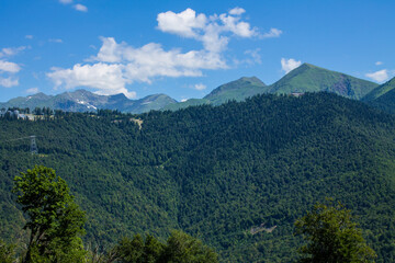 Beautiful panoramic mountain landscape with green trees and mountain slopes on a sunny summer day in Krasnaya Polyana in Russia