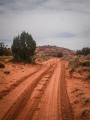 Red sandy dirt road with red sandstone mesa in background in Page Arizona desert