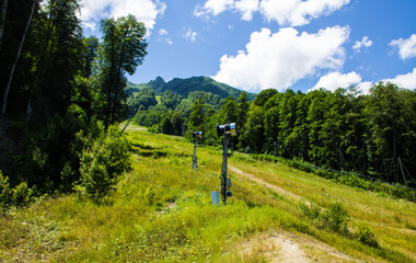 Beautiful panoramic landscape - mountain trail among green mountains and hills on a sunny summer day in Krasnaya Polyana in Russia
