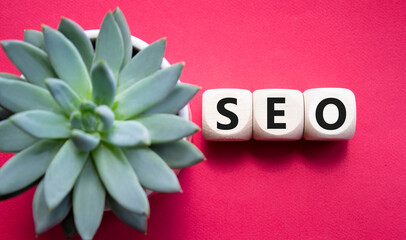 SEO - Search Engine Optimization symbol. Wooden blocks with words SEO. Beautiful red background...