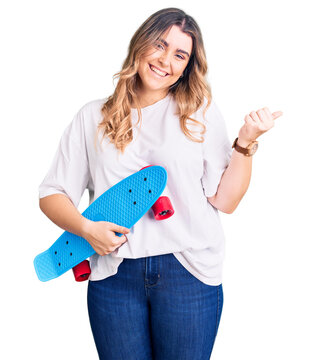 Young caucasian woman holding skate smiling happy pointing with hand and finger to the side