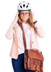 Young caucasian woman wearing bike helmet and leather bag suffering from headache desperate and stressed because pain and migraine. hands on head.