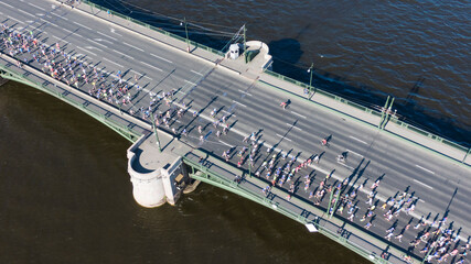 Aerial View of Marathon Runners on a Bridge Crossing a River. A city marathon, a crowd of athletes running across the bridge, an active lifestyle.