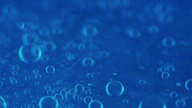 Air bubbles. Fizzy texture. Defocused blue color shiny gel water oxygen circles mineral hydrating cosmetics spinning abstract background.