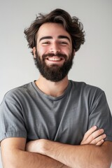 Obraz premium A man with a beard smiling and crossing his arms. Suitable for business or casual concepts