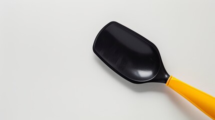 A black plastic spade with a yellow handle, typically used as a utensil for a frying pan, showcased on a white background.