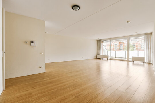 Bright empty room with a large window and wooden floor