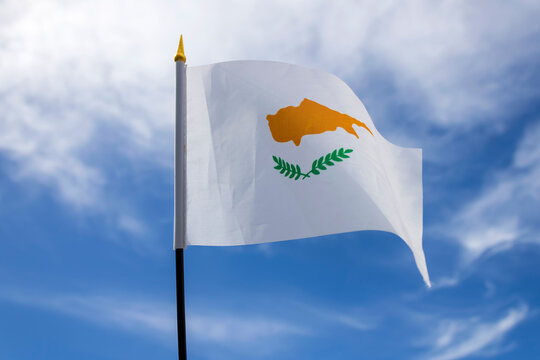 Cypriot national flag fluttering in the wind  in front of blue sky with white clouds