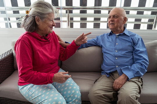 Elderly couple conversing on sofa in homely setting