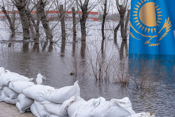 Flooding in the city of Kazakhstan in 2024.Sandbags and banner of Kazakhstan drowning in meltwater on background.