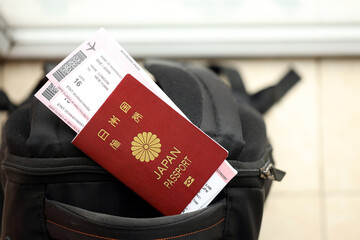 Japan passport with airline tickets on touristic backpack close up. Tourism and travel concept