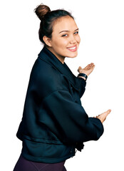 Young hispanic girl wearing sportswear inviting to enter smiling natural with open hand