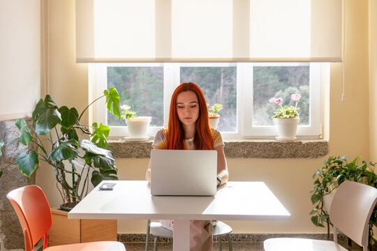 Redheaded woman working on laptop in serene nature retreat