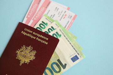 French passport and euro money with airline tickets on blue background close up. Tourism and travel concept