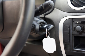 Close-up view of a car's ignition with a key inserted and a blank keychain, ready for branding or personalization, inside a vehicle interior