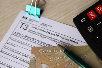 Canadian T3 tax form Trust income tax and information return lies on table with canadian money bills close up. Taxation and annual accountant paperwork in Canada