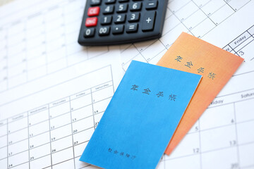Japanese pension insurance booklets on table with calculator on table close up