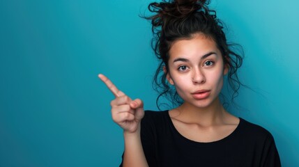 A woman with a messy top knot pointing at the camera. Suitable for lifestyle and fashion concepts