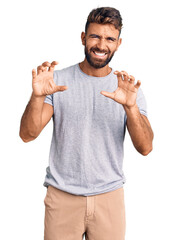 Young hispanic man wearing casual clothes smiling funny doing claw gesture as cat, aggressive and...