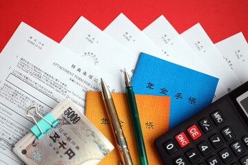 Japanese pension insurance booklets on table with yen money bills, pen and calculator on table close up
