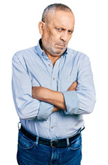 Senior man with grey hair and beard wearing casual blue shirt skeptic and nervous, disapproving expression on face with crossed arms. negative person.