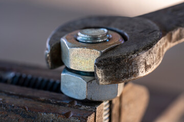 Loosening the nut using a wrench and a vise. Using old spanner wrench and clamp to remove nut from bolt, closeup