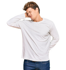 Handsome caucasian man wearing casual white sweater suffering of neck ache injury, touching neck with hand, muscular pain