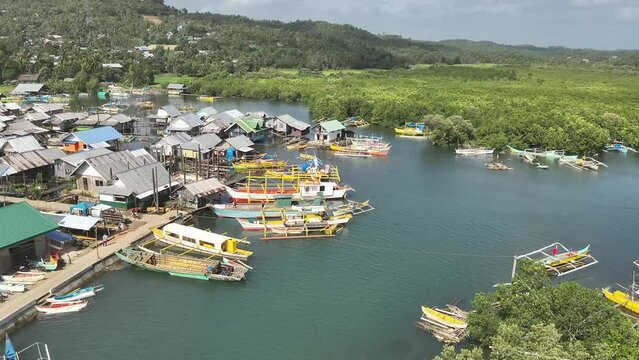 Aerial video of boats anchored in the sea near wooden houses in a fishing village, Socorro