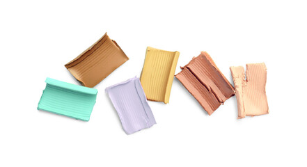 Samples of different color correcting concealers on white background, top view