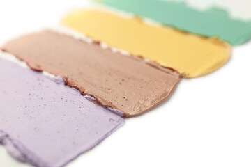 Samples of different color correcting concealers on white background, closeup